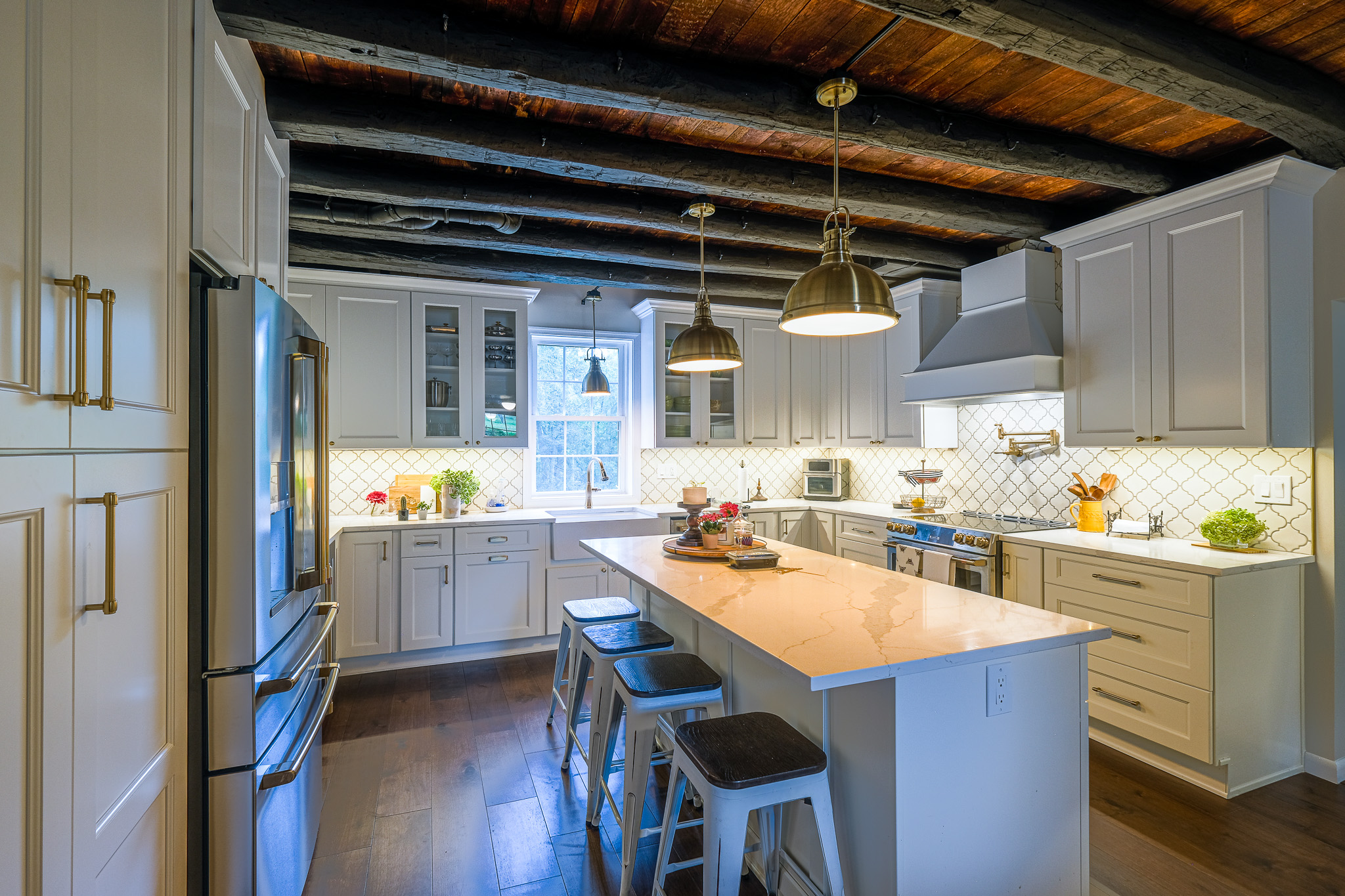 Modern kitchen with white cabinetry, a central island, and wooden beam ceiling.