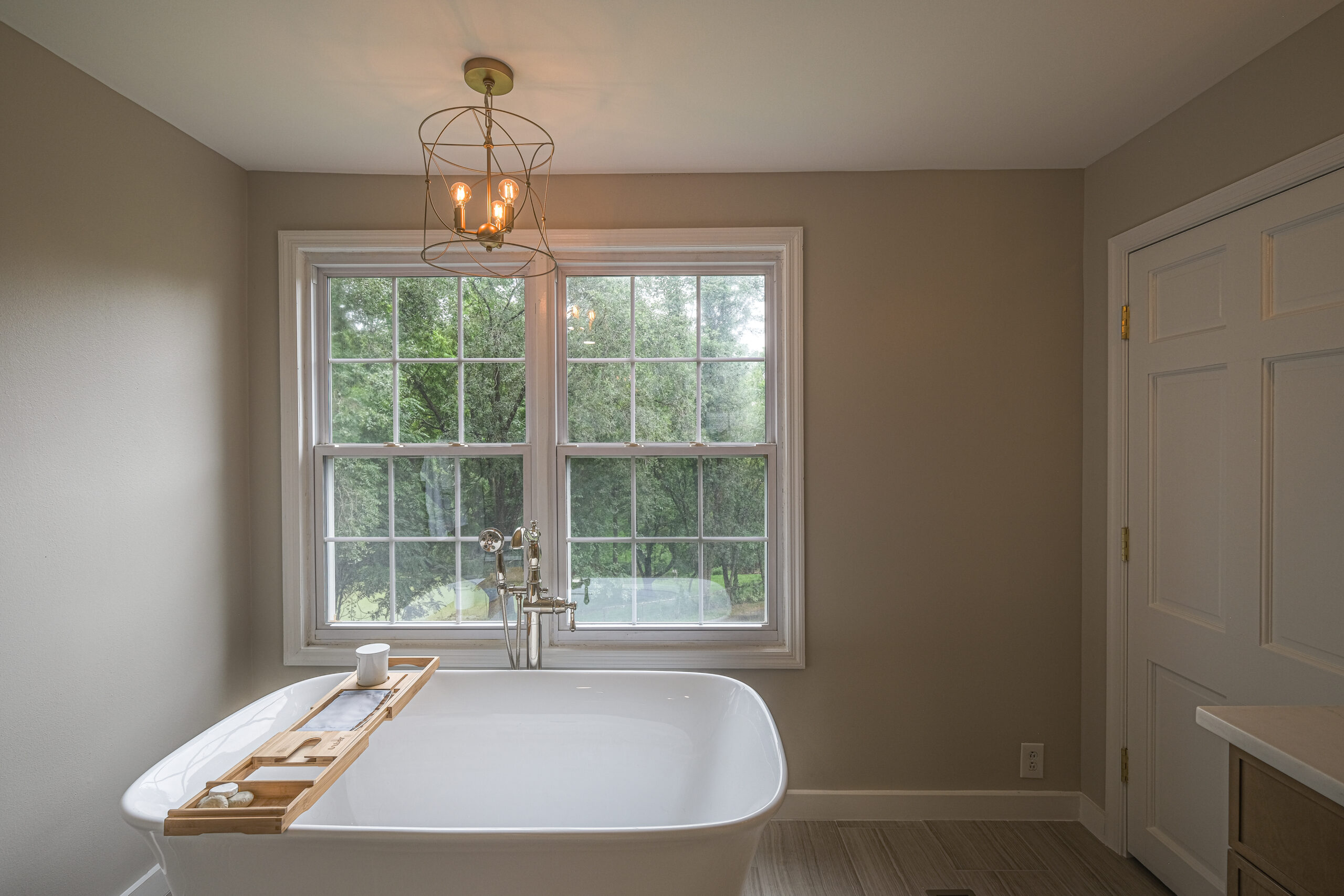 Freestanding bathtub next to a large window in a minimalist bathroom.