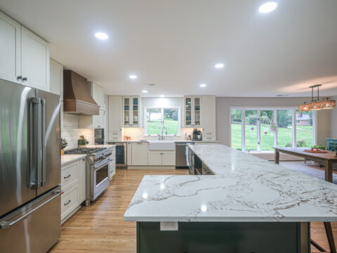Spacious modern kitchen with marble countertops, stainless steel appliances, and a view of the backyard.