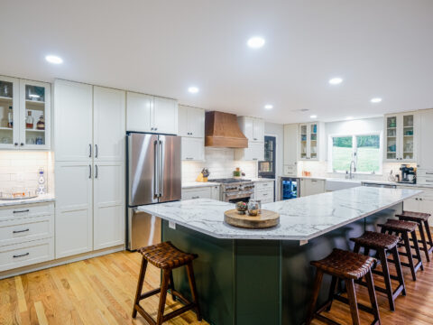 Full view of a modern kitchen with a quartz island, bar stools, and stainless steel appliances.