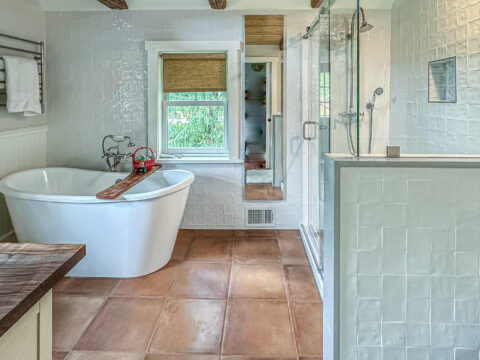 Freestanding bathtub and glass-enclosed shower in rustic-modern bathroom.