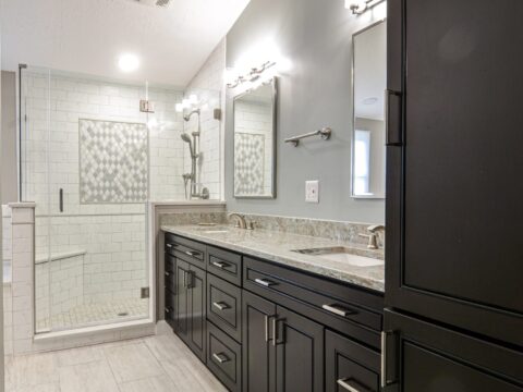 Modern bathroom with double vanity and glass-enclosed shower.