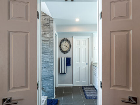 View of a modern bathroom with double doors leading to a sleek design featuring a tiled wall
