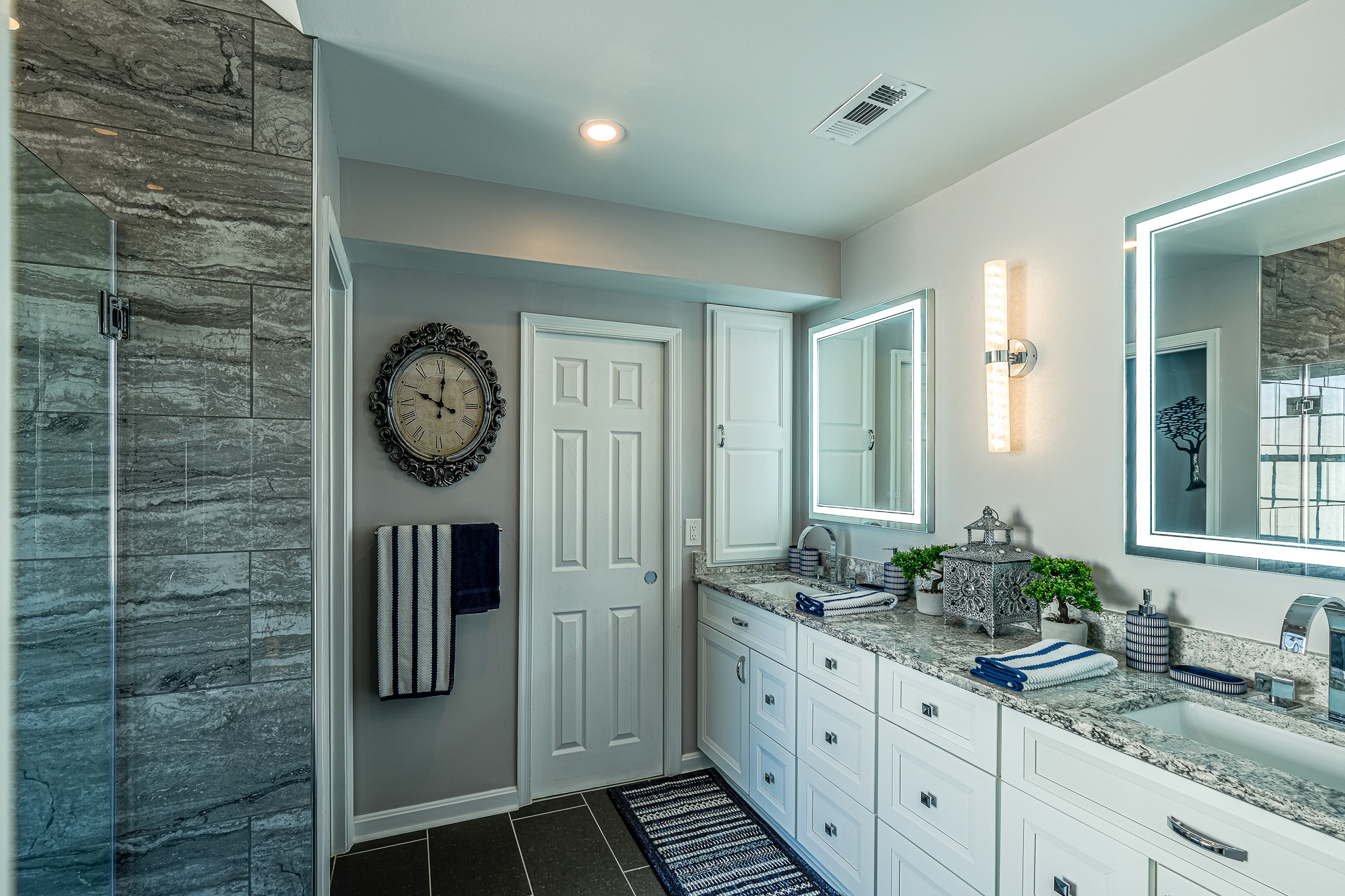 Modern bathroom with a large vanity, granite countertop, and dual illuminated mirrors above