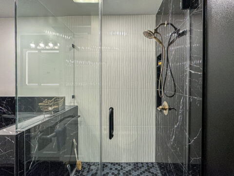 Frameless Glass Shower with Wave-Texture Tile and Black Marble Accent