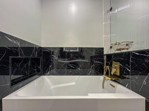 Freestanding Soaking Tub with Black Marble Surround and Brushed Gold Fixtures